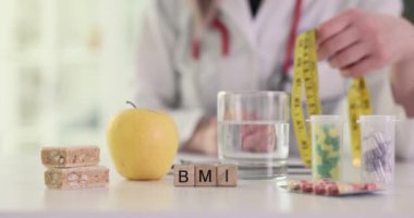 Profesyonel doktor, hastanın vücut kitle indeksini hesaplar. Minyatür tahta bloklar doktor masasında BMI kısaltması oluşturur. Yavaş çekim