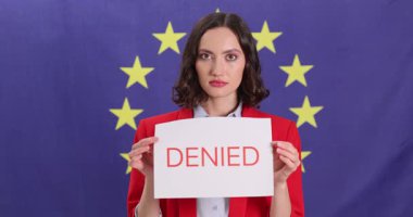 Parlak takım elbiseli işkadını başvuru sahiplerine turist vizesinin reddedildiğini bildiriyor. Ciddi bir kadın üzerinde SchENGEN VISA ve DENIED yazılı işaretler taşıyor.