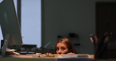Ürkek iş kadını fırtınada loş bir ofiste saklanıyor. Dehşete düşmüş kadın ofis çalışanı derin bir nefes alıyor ve görünmemeye çalışıyor. Yavaş çekim