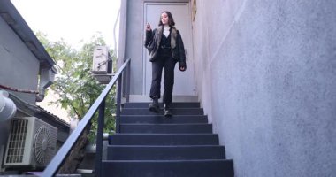 Deri ceketli kadın sigara içerek merdivenlerden iniyor. Genç bir kadın işten izin alıp ağır çekimde kötü alışkanlıkların tadını çıkarıyor.