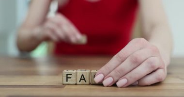 Tahta küpler düzgün masa yüzeyinde düzenlenmiş kelime FACT. Kadın, sahte kelime yaratmak için masanın üstündeki harfleri değiştiriyor. Yavaş çekim