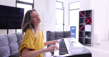 Genç kadın synthesizer 'da çok güzel melodi çalıyor. Kadın, synthesizer klavyesinde tuşlara basar ve güvenli bir şekilde şarkı söyler. Yavaş çekim