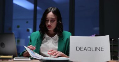 Karanlık ofiste Deadline tabelasıyla çalışan ciddi bir kadın. İş sorumlulukları ve geç saatlere kadar kalan görevlerle kadın yöneticiler ilgilenir