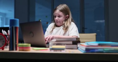 Laptop 'ta ödevlerini yapmak için acele eden duygusal küçük kız tipleri. Komik liseli kız gece geç saatlerde bilgisayarda ödevini yazıyor.