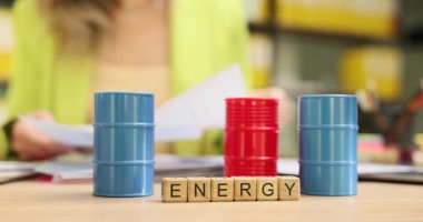 Yetenekli iş kadını, enerji arzıyla ilgili önemli sözleşmeleri inceliyor. Minyatür ahşap küpler küçük petrol varillerine karşı ENERGY kelimesi oluşturur.