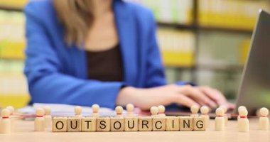 Kadın ofis çalışanı, masadaki piyonların yakınındaki dış kaynak kullanımını araştırıyor. İş kadını şirket için dış kaynak stratejileriyle ilgili belgeleri gözden geçirdi