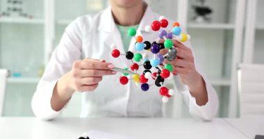 Bir bilim adamı modern bir laboratuvarda detaylı bir moleküler modeli inceleyerek bilimsel araştırmalar ve keşifler sergiliyor.