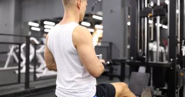 Odaklanmış bir adam spor salonunda çalışıyor. Güç ve zindelik için kablo makinesini etkili bir şekilde kullanıyor.