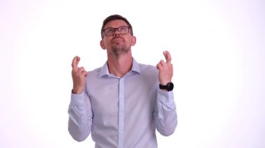 Gözlüklü bir adam parmaklarını çapraz yapıyor, derin bir umut ve gelecek için büyük bir beklenti besliyor.