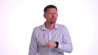 Bir adam derin bir düşüncelere dalmış, profesyonel bir ortamda gözlüğünü incelikle ayarlıyor.