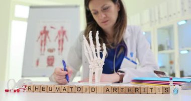 Bir sağlık uzmanı romatizmanın karmaşıklığını tartışmak için insan elinin detaylı bir modelini inceliyor.