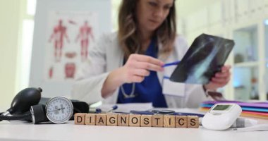 Kendini adamış bir sağlık uzmanı masadaki çeşitli teşhis araçlarını kullanarak röntgenleri ayrıntılı bir şekilde inceliyor.