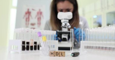 Bir araştırmacı, detaylı çalışması için HDL kolesterol seviyelerine odaklanarak, örnekleri mikroskop altında analiz eder.