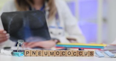 Bir doktor zatürree teşhisi koymak için röntgeni dikkatlice değerlendirirken Scrabble fayansları pnömokok kelimesini heceliyor.