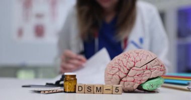 DSM5 'in görsel bir temsili, beynin bir çizimi ve çeşitli tıbbi malzemelerle birlikte.