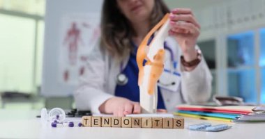 Bir sağlık uzmanı eğitim amaçlı tıbbi bir ortamda diz modeliyle tendonit gösterir