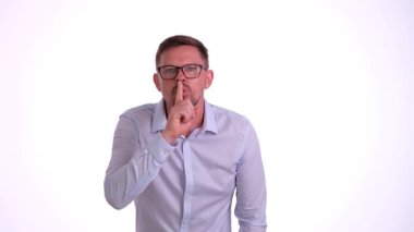 Gözlüklü bir adam sessizlik işareti veriyor, gizlilik ve gizliliğin önemini vurguluyor.