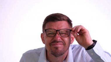 Gözlüklerini düzeltirken şaşkınlığını gösteren bir adam temiz ve düzenli bir stüdyo ortamındadır.