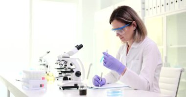Kendini işine adamış bir kadın bilim adamı, parlak bir laboratuarda mikroskopla karmaşık bir araştırma yürütüyor.