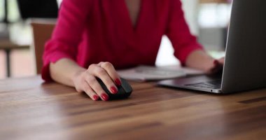 Modern bir çalışma alanında bilgisayar faresiyle ustalıkla gezinirken dikkatle dizüstü bilgisayar kullanan odaklanmış bir kadın.