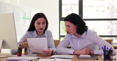 Modern bir ofis ortamında, takım çalışması ve üretkenlik sergileyen iki kadın işbirliği yapıyor..