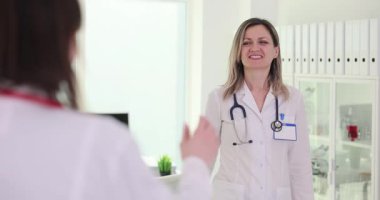 Bayan tıp çalışanı klinikteki bayan meslektaşıyla iyi bir ruh hali paylaşıyor. Mutlu kadın doktorlar hastane koridorunda yürürken beşlik çakıyor.