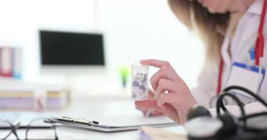 Deneyimli kadın doktor ilaç hapları için reçete yazıyor. Beyaz önlüklü doktor kapsüllerin dozajını ve kullanım sıklığını yazıyor. Yavaş çekim