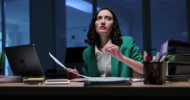 Düşünceli iş kadını gece geç saatlerde ofiste çalışarak sorunlara çözüm arıyor. Kadın, şirket ortamında içgörü belgelerinin tutulmasını bekliyor.