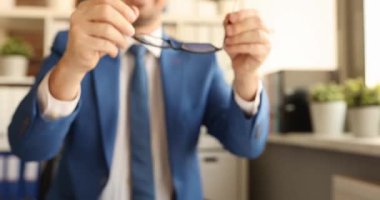 Mutlu bir çalışan gülümserken gözlük takar. Sakallı bir ofis çalışanı sıcak odanın penceresinin yanında kollarını kavuşturarak görev yapmaya hazırlanıyor.