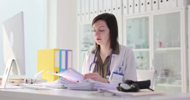 Yorgun doktor, hasta geçmişinin sayfalarını inceliyor. Doktorlar tıbbi kayıtları inceler ve alnındaki teri siler. Yavaş çekim