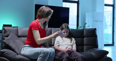 Kızgın anne kızını azarlıyor ve akıllı telefonu oturma odasına götürüyor. Alet bağımlısı küçük kız ve duygusal kadın ebeveyn kanepeye oturur.