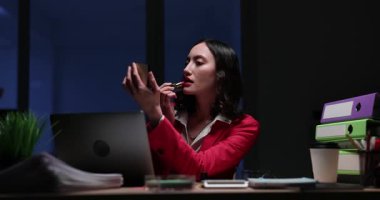 İş kadını elinde küçük bir ayna tutuyor ve dudaklarına kırmızı ruj sürüyor. Kadınlar kusursuz görünmesi için dudaklarını birbirine bastırır. Yavaş çekim