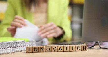 Kadın dizüstü bilgisayarda çalışıyor ve Yenilik masasının yanındaki bloklarda belgeler var. Profesyonel işçi ortamı yaratıcılığa ve ofiste yeni fikirlere odaklandı