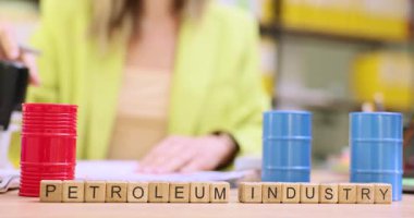 Bayan Yönetici Petrol endüstrisi deyimiyle blokların yanındaki masada oturan belgeleri imzalar ve pullar. Para ve renkli petrol varilleri ofisteki masada.