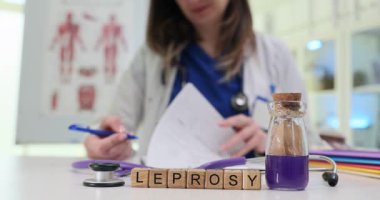 Masasında cüzam olan tahta bloklar ve dokümanlarda paltolu kadın doktor. Modern klinikte cüzzam tedavisine ilişkin tıbbi içerik