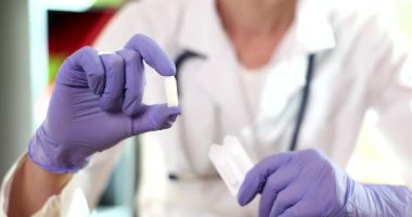 Kadın hekim randevuda bir kutu fitille el ele tutuşur. Deneyimli doktor reçeteli fitillerin faydalarını tanımlıyor. Yavaş çekim