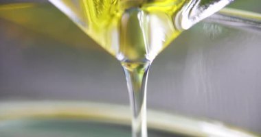 Şeffaf sarı yağ akışı ışık arka planına yavaşça döküldü. Bilimsel laboratuvarda kozmetik ve tıbbi ürün sunumu