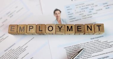 Tahta bloklar Kelime EMPLOYMENT oluşturur. Kadın pasaportu ve yasal sözleşme için vize başvurusu formlarıyla kaplı küçük küpleri masaya yerleştirin