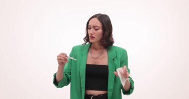 Hasta kadın elinde mendille beyaz duvara sümkürdü. Termometre dijital ekranda yüksek sıcaklık okunduğunda kadın kaşlarını çatıyor. Yavaş çekim
