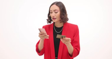 Kadın elinde banka kartı tutuyor ve beyaz arka planda telefona kart numarası yazıyor. Kadın akıllı telefondan online alımı tamamlıyor. Yavaş çekim