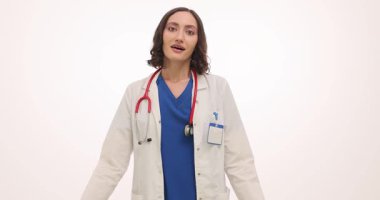 Beyaz önlüklü gülümseyen kadın doktor elini göğsüne koydu başını yana yatırdı. Mutlu kadın ifadesi samimiyet ve minnettarlığı önerir.