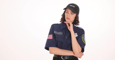 Koyu mavi üniformalı, şapkalı ve rozetli bir kadın düşünceli bir görünüm ve çenesinde bir el ile ayakta duruyor. İşteki polis memuru bilgi düşünüyor