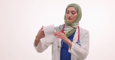 Steteskopla tesettürlü bir doktor açılır ve uzun kağıt rulolarına şablonlu bakar. Kadın tuvalet kağıdını incelerken hijyen kurallarını gösteriyor.