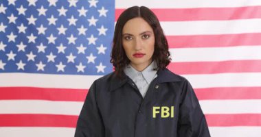 Kadın FBI ajanı, Amerikan bayrağına karşı büyük bir paket uyuşturucu ve kelepçe taşıyor. Ciddi bir kadın, el konulmuş uyuşturucu gösteriyor. Yavaş çekim