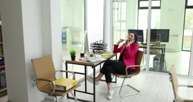 Mutlu kadın yönetici iş yerinde otururken akıllı telefondan konuşur. İş kadını, şirket ofisindeki çağrı yoluyla müşteriye danışıyor. İş iletişimi