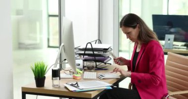 Odaklanmış iş kadını iş yerinde hesap makinesiyle para sayar. Kadın girişimci şirket ofisindeki kazancı kontrol ediyor. Mali yönetim