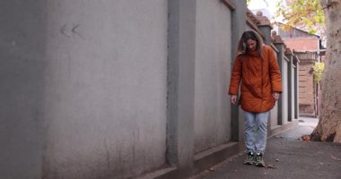 Kadın şehir caddesinde yürüyor ve kaldırım boyunca bağlanmamış dantel görüyor. Dişi dizler yavaşça bağcıkların ve bağların uçlarını topluyor. Yavaş çekim