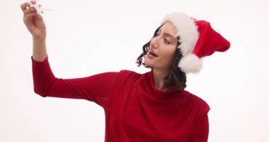 Noel Baba şapkalı kadın küçük oyuncak bir uçak tutuyor ve rüya gibi bir gülümsemeyle oynuyor. İfade ve uçak, tatil seyahatlerinin hayal edilmesini ve beklenmesini öneriyor