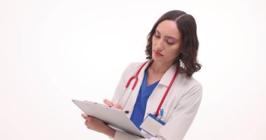 Odaklanmış ifadesi olan kadın hekim beyaz arka plana karşı hasta tedavisi planı oluşturur. Doktor kağıda not alır. Yavaş çekim