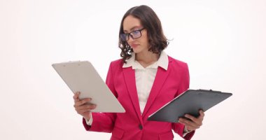 Düşünceli iş kadını, beyaz arka plandaki panolara bakan belgeleri karşılaştırıyor. Kadın yönetici kağıtlardaki hataları çözmeye çalışırken omuz silkiyor